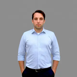 A man standing straight facing the camera, hands in pockets,