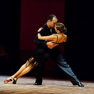 Two tango dancers in a close embrace, the man dipping the wo