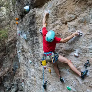 A rock climber clinging to a cliff face with arms and legs e