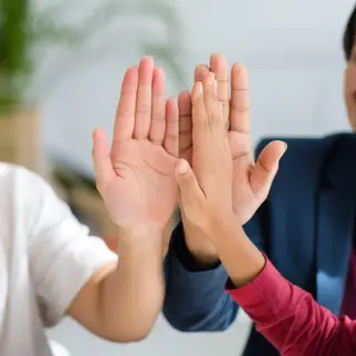 Two people doing a high-five, palms meeting with all fingers