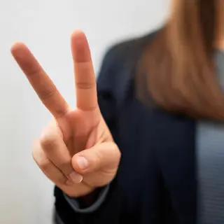 A person making a peace sign with their right hand, clearly 