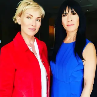 Two women standing side by side: one with short blonde hair 