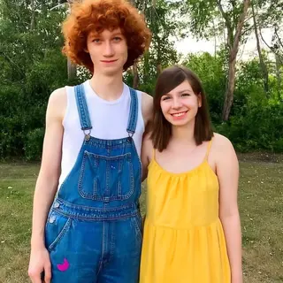 Two friends posing: one tall with curly red hair in denim ov