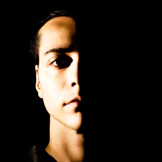 A portrait with dramatic split lighting — half the face brig