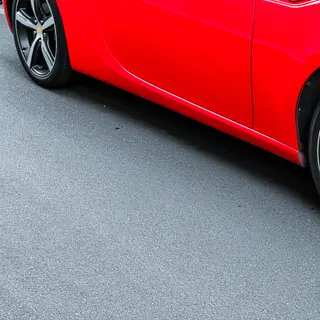 A bright red sports car parked on a gray asphalt road — the 