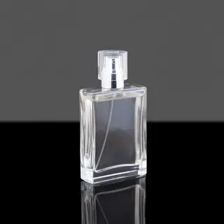 A clear glass perfume bottle on a reflective black surface w