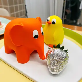An orange elephant, a yellow penguin, and a silver strawberr