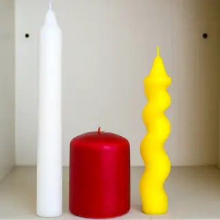 A tall thin white candle, a short fat red candle, and a medi
