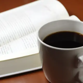 A coffee mug next to an open book on a desk