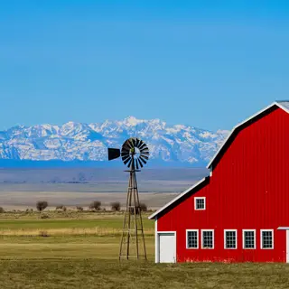 A landscape with a red barn in the foreground at large scale