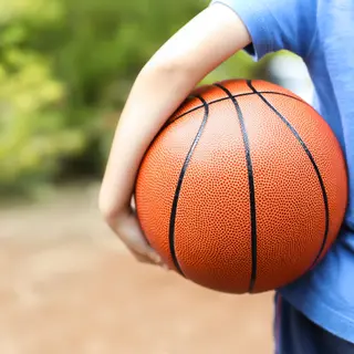 A child holding a basketball, both at correct relative sizes