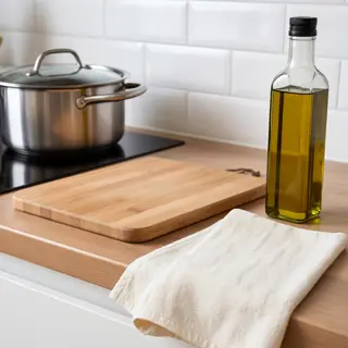 A kitchen counter with a stainless steel pot, a wooden cutti
