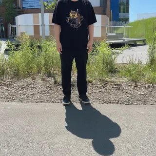 A person standing outdoors at midday with a short shadow dir