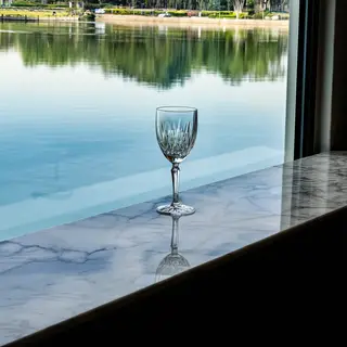 A crystal wine glass on a polished marble counter next to a 