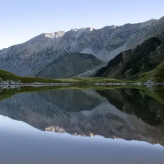 A mountain range reflected in a still alpine lake, with the 