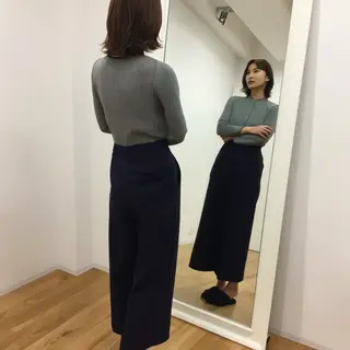 A woman standing in front of a full-length mirror, her refle