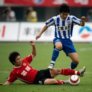 Two soccer players mid-tackle, one sliding and the other jum