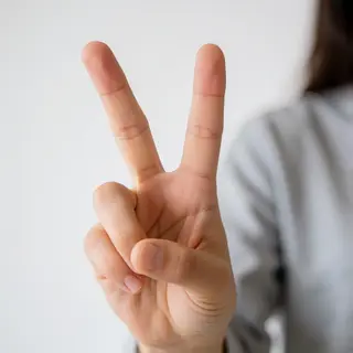 A person making a peace sign with their right hand, clearly 