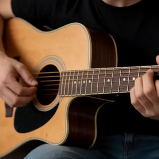 A person playing an acoustic guitar with left hand on the fr