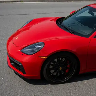 A bright red sports car parked on a gray asphalt road — the 