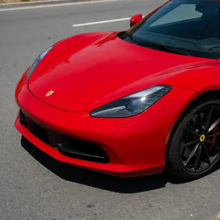 A bright red sports car parked on a gray asphalt road — the 