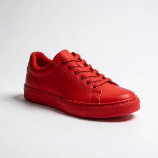 A single red sneaker on a clean white background with soft s