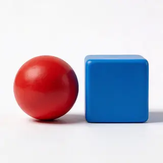 A red ball and a blue cube sitting side by side on a white s