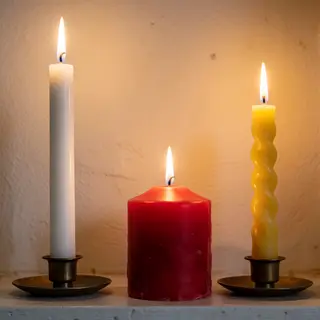 A tall thin white candle, a short fat red candle, and a medi