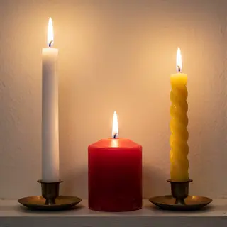 A tall thin white candle, a short fat red candle, and a medi