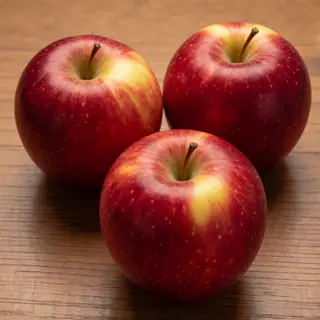 Exactly 3 red apples arranged on a wooden table