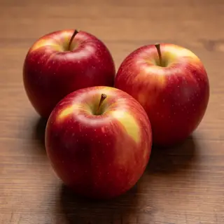Exactly 3 red apples arranged on a wooden table