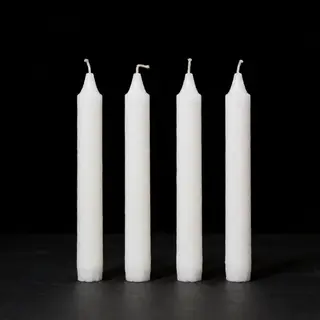 Exactly 4 white candles standing on a dark surface