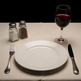 A dinner table scene with a plate, fork, knife, wine glass, 