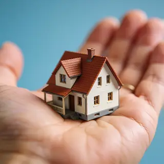 A miniature house sitting on the palm of someone's hand