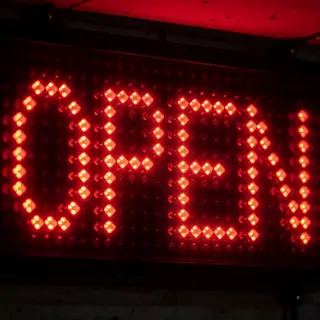The word 'OPEN' displayed on a red LED sign with glowing pix