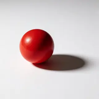 A red sphere on a white surface with a single shadow cast to