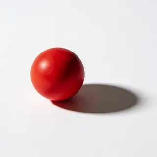 A red sphere on a white surface with a single shadow cast to