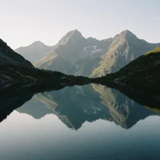 A mountain range reflected in a still alpine lake, with the 