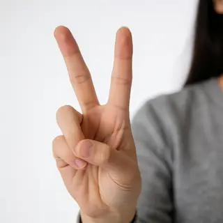 A person making a peace sign with their right hand, clearly 