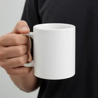 A person holding a white ceramic coffee mug by the handle wi
