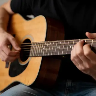 A person playing an acoustic guitar with left hand on the fr