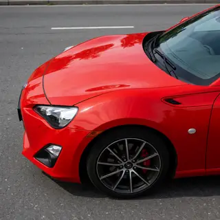 A bright red sports car parked on a gray asphalt road — the 