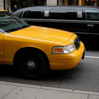 A yellow taxi and a black limousine parked next to each othe