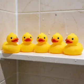 Exactly 5 yellow rubber ducks sitting in a row on a bathroom