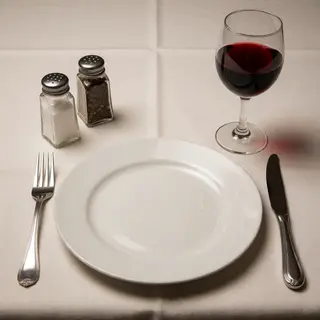 A dinner table scene with a plate, fork, knife, wine glass, 