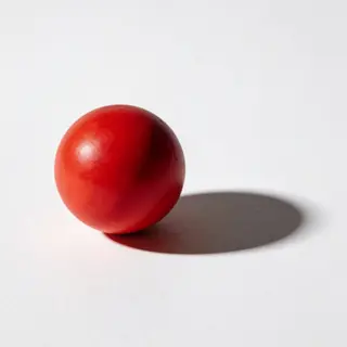 A red sphere on a white surface with a single shadow cast to