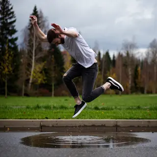 A man captured mid-jump over a puddle, body in the air with 