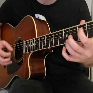 A person playing an acoustic guitar with left hand on the fr
