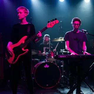 Three musicians on stage: a tall woman with short pink hair 