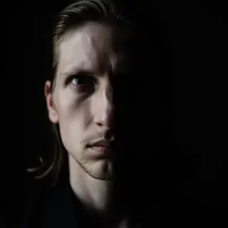 A portrait with dramatic split lighting — half the face brig